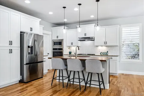a kitchen with stainless steel appliances granite countertop a stove a refrigerator a kitchen island a table and chairs
