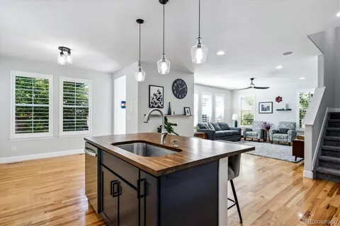 a room with stainless steel appliances granite countertop a sink a kitchen island with wooden floor and cabinets