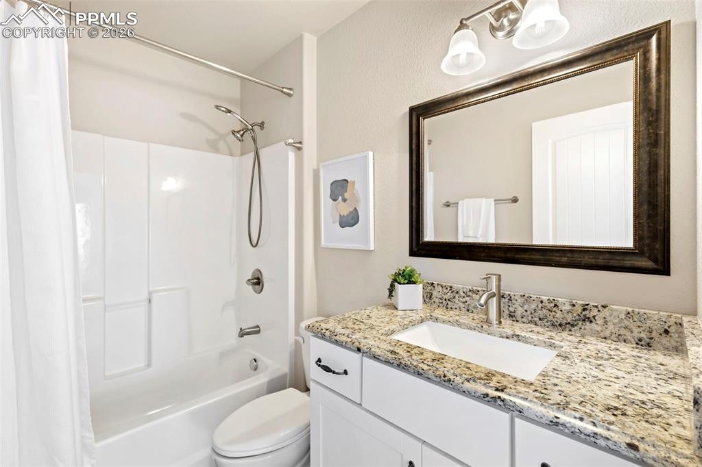 6528 Watusi Road Peyton, CO 80831 - Photo 19 of 27 a bathroom with a granite countertop sink toilet mirror vanity and shower