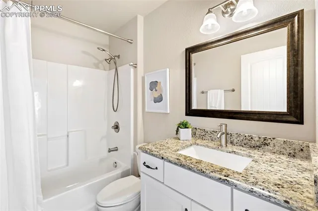 a bathroom with a granite countertop sink toilet mirror vanity and shower