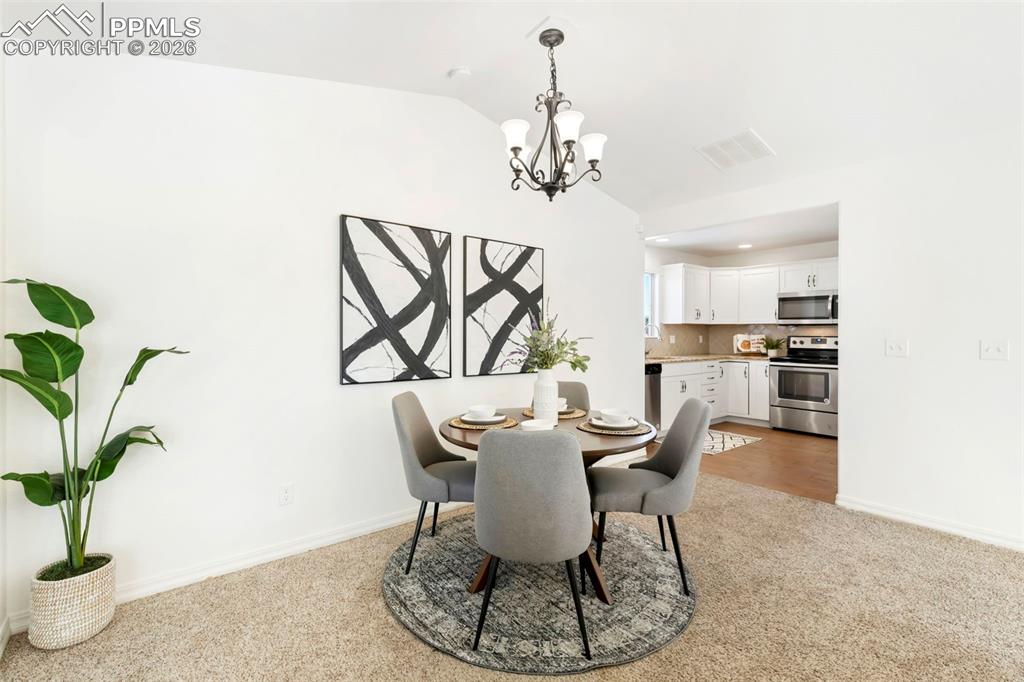 6528 Watusi Road Peyton, CO 80831 - Photo 8 of 27 a view of a dining room with furniture a chandelier and wooden floor
