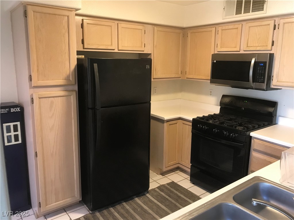 3425 East Russell Road, Unit 170 Las Vegas, NV 89120 - Photo 11 of 13 Kitchen featuring light tile patterned flooring, light brown cabinetry, black appliances, and light countertops
