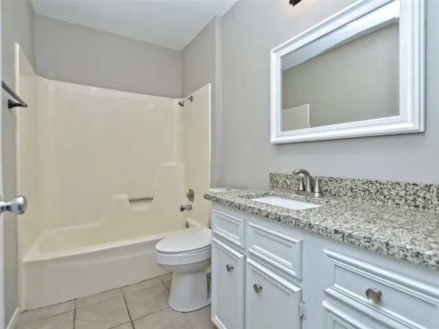 a bathroom with a granite countertop sink a toilet and a bathtub