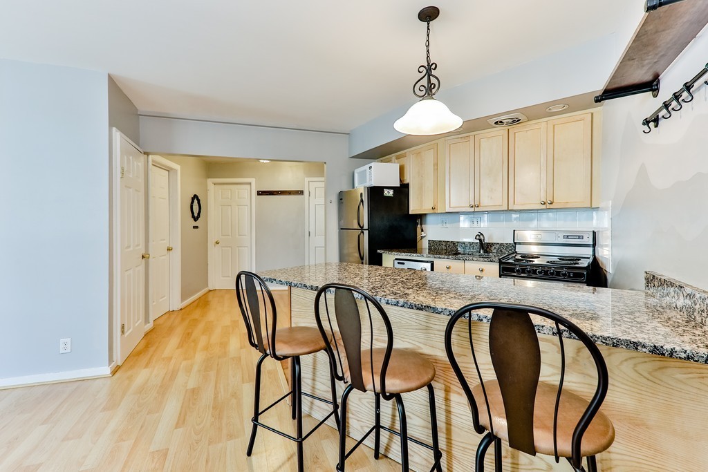 512-516 Green Street, Unit 1D Cambridge, MA 02139 - Photo 2 of 9 a kitchen with stainless steel appliances granite countertop a sink a stove a refrigerator with a dining table and chairs