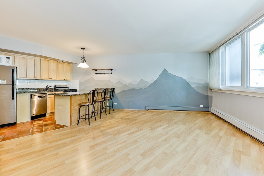 512-516 Green Street, Unit 1D Cambridge, MA 02139 - Photo 4 of 9 a view of kitchen and empty room with wooden floor