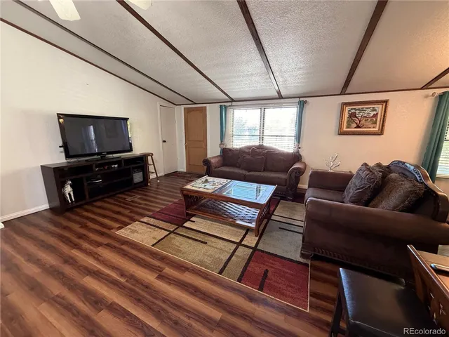 a living room with furniture a flat screen tv and a refrigerator