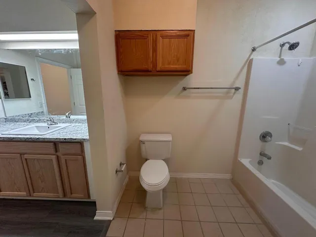 a bathroom with a granite countertop toilet and a sink