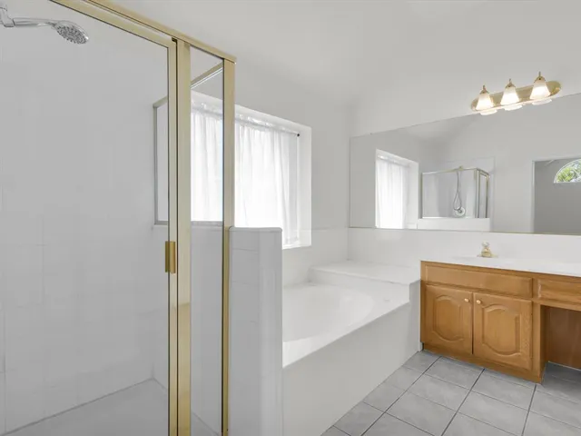 a spacious bathroom with a tub sink and mirror