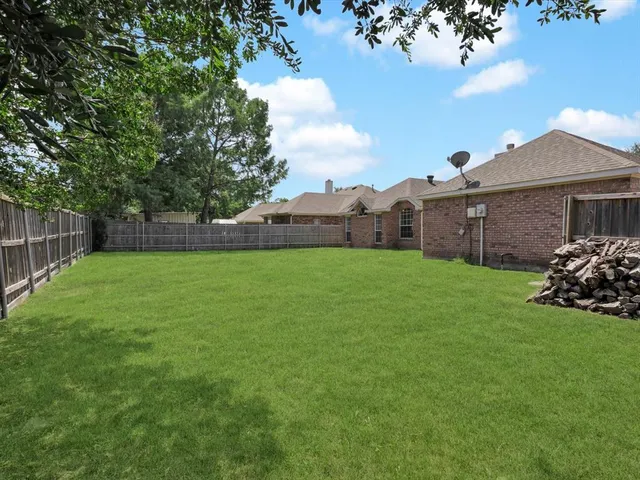 a view of a house with a yard and a large tree