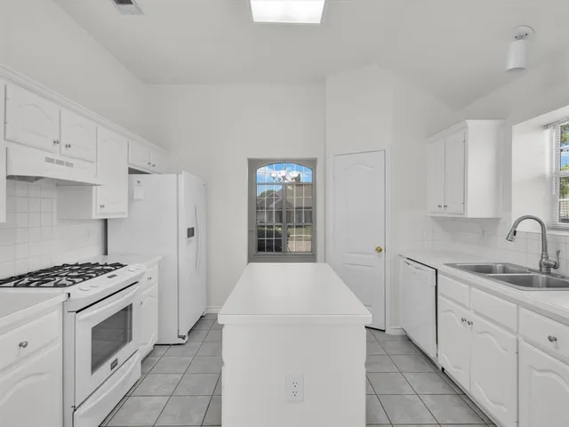 a kitchen with granite countertop a sink stove and cabinets