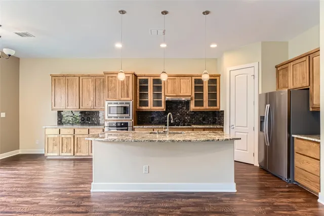 a large kitchen with stainless steel appliances granite countertop a large center island and a wooden floor