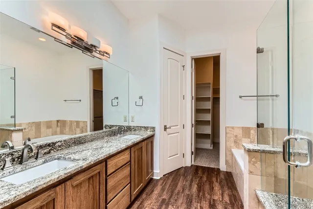 a bathroom with a granite countertop sink a mirror and shower