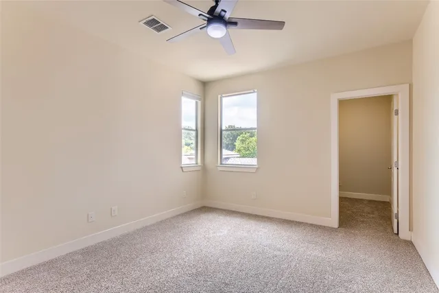 an empty room with a window and a fan