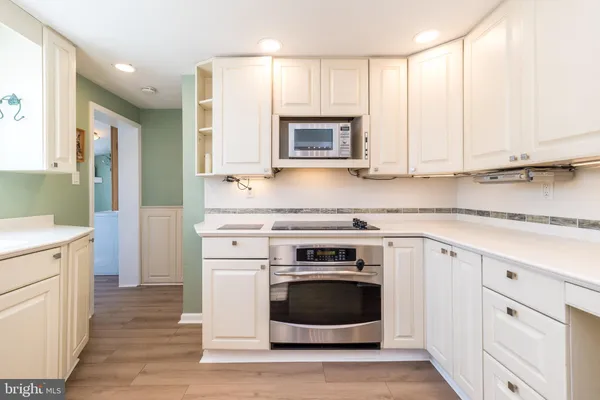 a kitchen with stainless steel appliances white cabinets and a stove top oven