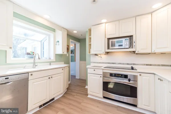 a kitchen with cabinets stainless steel appliances a sink and wooden floor