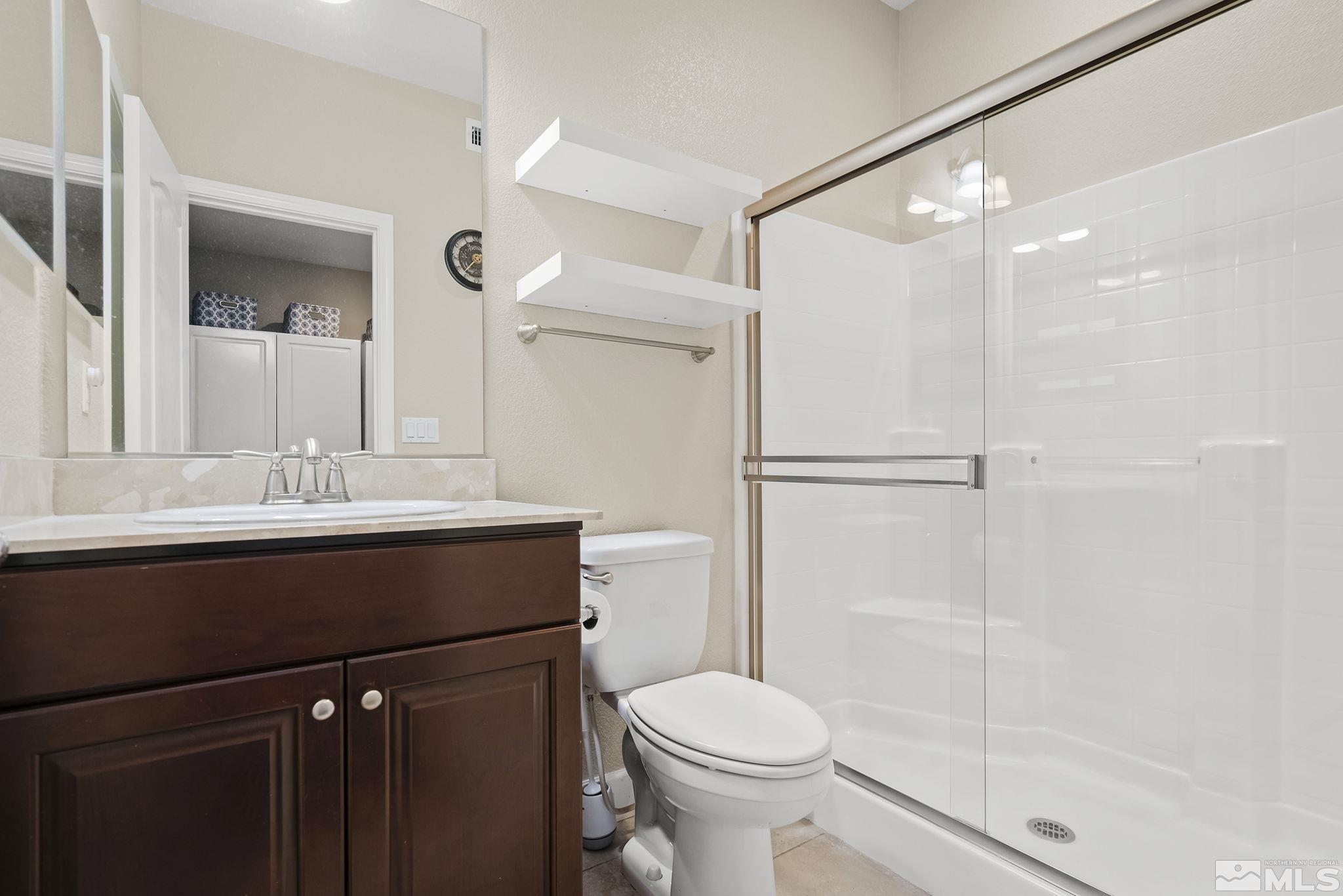 10848 Walnut Ridge Drive Reno, NV 89521 - Photo 22 of 32 a bathroom with a sink a toilet a mirror and shower