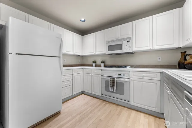 a kitchen with white cabinets and white stainless steel appliances