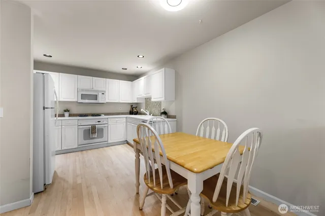 a kitchen with stainless steel appliances granite countertop a stove top oven a sink dishwasher a dining table and chairs with wooden floor