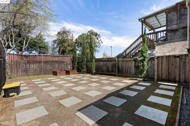 a view of a backyard with wooden fence and trees