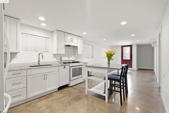 a kitchen with white cabinets and chairs