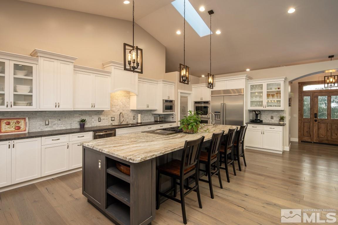4610 Tybo Road Reno, NV 89521 - Photo 4 of 40 a kitchen with stainless steel appliances granite countertop a stove top oven a refrigerator a sink and white cabinets with wooden floor