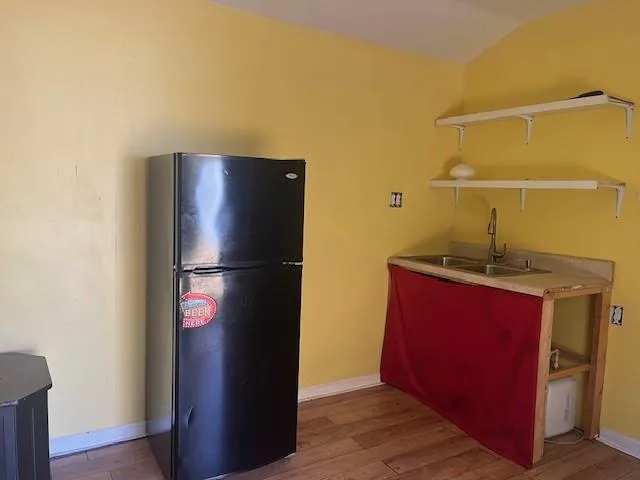 a kitchen with a refrigerator and a wooden floor