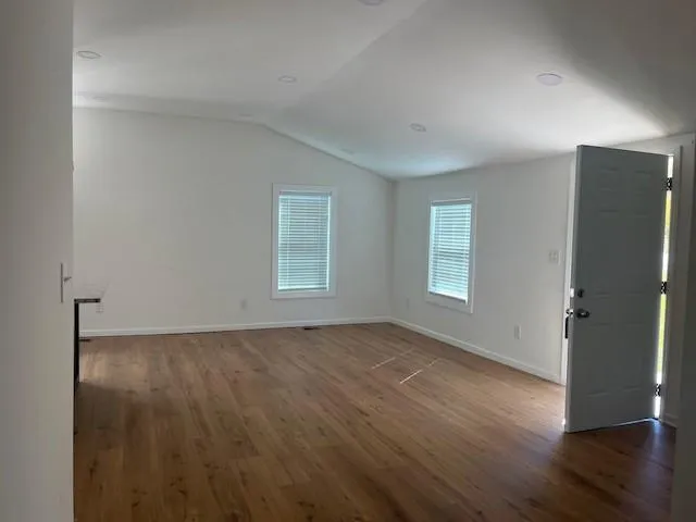 a view of an empty room with wooden floor and a window