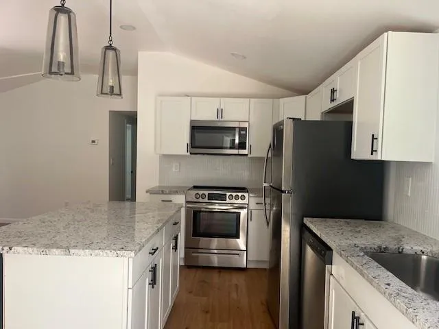a kitchen with granite countertop a stove sink and refrigerator