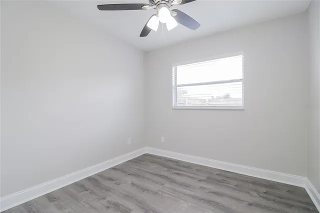 an empty room with ceiling fan and window