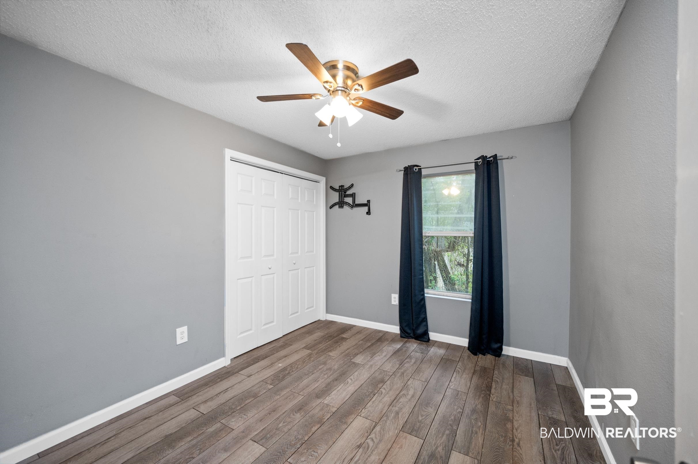 906 North Cedar Street Foley, AL 36535 - Photo 9 of 24 Unfurnished bedroom featuring a closet, wood-type flooring, ceiling fan, and a textured ceiling