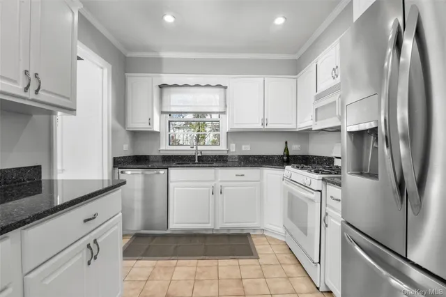 a kitchen with stainless steel appliances granite countertop a sink a stove a refrigerator and cabinets