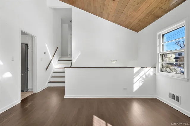 a view of an empty room with wooden floor and stairs