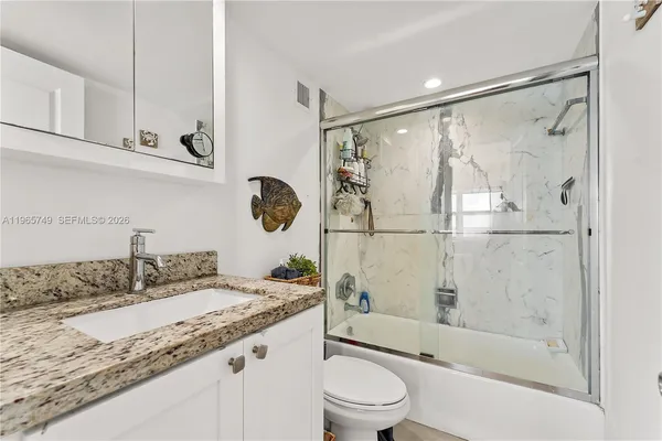 a bathroom with a granite countertop sink mirror toilet and bathtub
