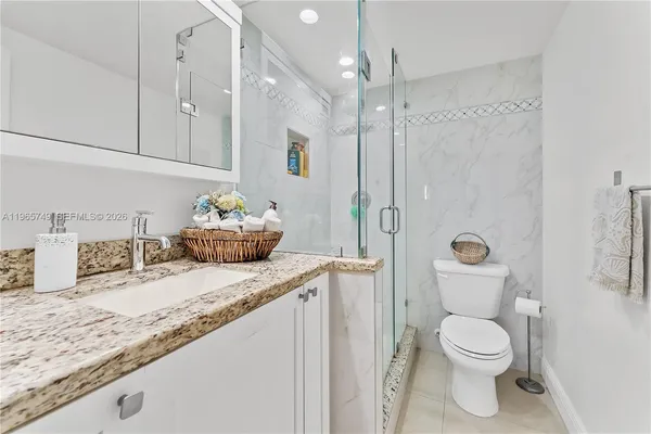 a bathroom with a granite countertop sink a toilet and a shower