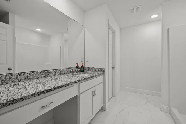 a bathroom with a granite countertop sink and a mirror
