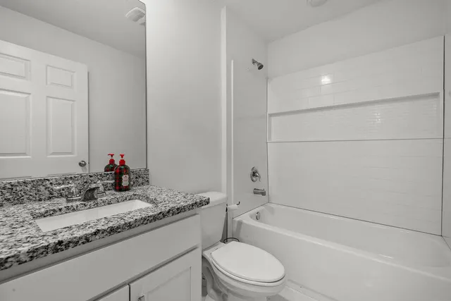 a bathroom with a granite countertop sink a toilet and bathtub