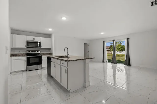 a kitchen with granite countertop a refrigerator and a stove top oven