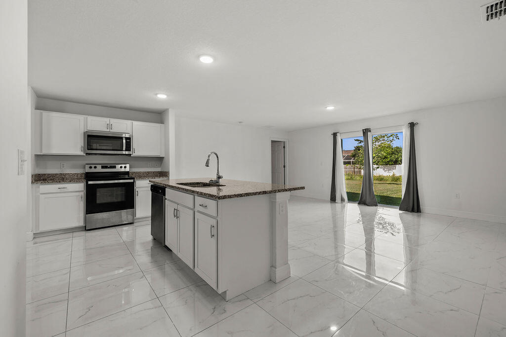 362 Northwest Bayshore Boulevard Port St. Lucie, FL 34983 - Photo 5 of 32 a kitchen with granite countertop a refrigerator and a stove top oven