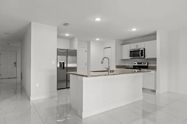 a kitchen with stainless steel appliances granite countertop a refrigerator and a stove