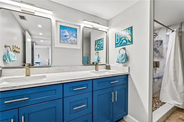a bathroom with a granite countertop double vanity sink and a mirror