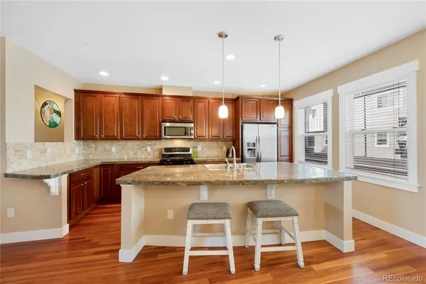 a kitchen with stainless steel appliances granite countertop wooden cabinets and wooden floor