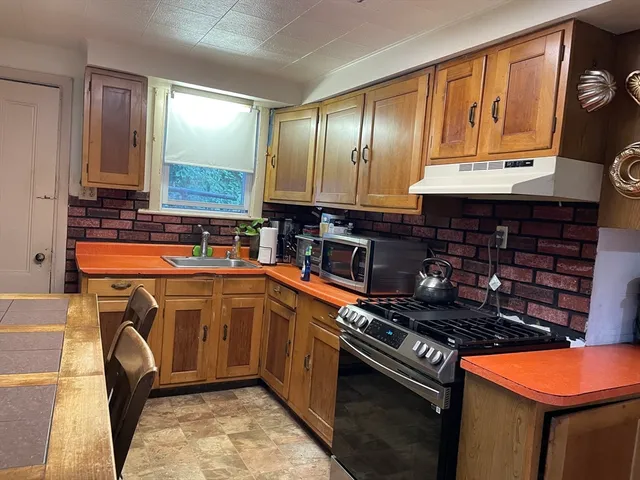 a kitchen with stainless steel appliances granite countertop a stove a sink and a microwave