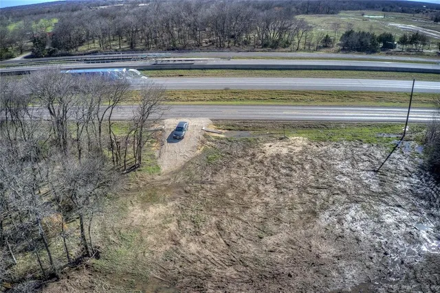a view of dirt field with trees in background