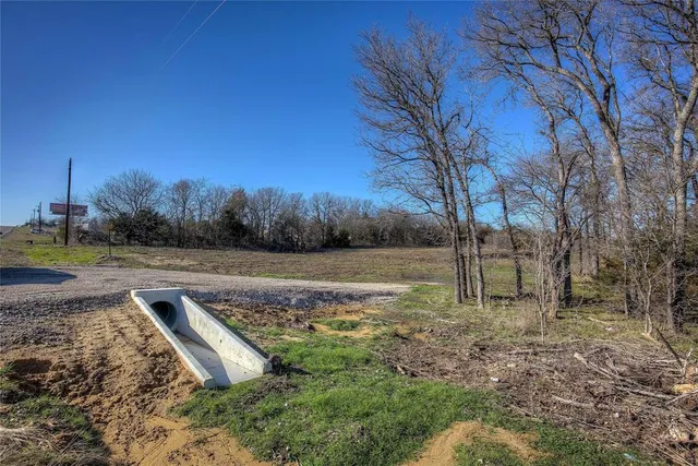a view of dirt field with trees in background