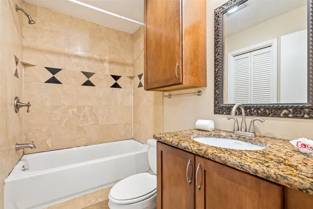 a bathroom with a granite countertop sink a toilet and bathtub