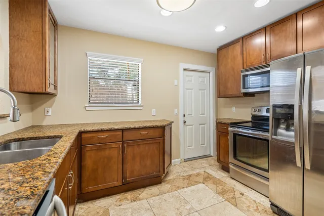 a kitchen with stainless steel appliances granite countertop a stove a sink and a microwave