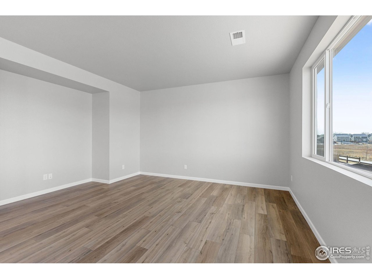 16953 Ballinger Circle Mead, CO 80542 - Photo 9 of 27 a view of an empty room with wooden floor and a window
