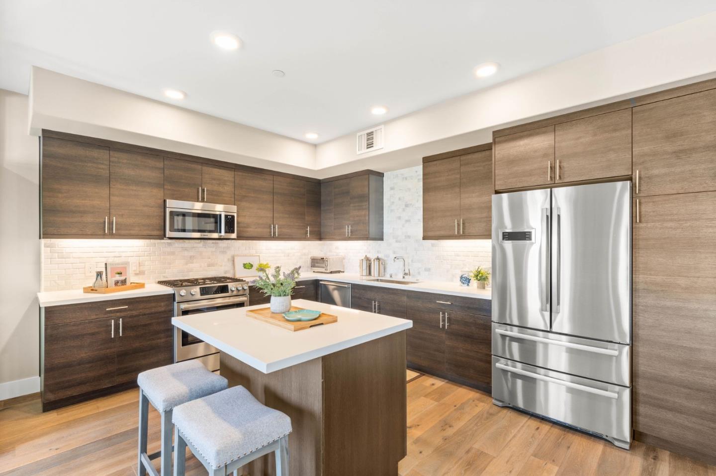 400 Mariners Island Boulevard, Unit 202 San Mateo, CA 94404 - Photo 6 of 31 a kitchen with a sink a refrigerator a stove and chairs with wooden floor