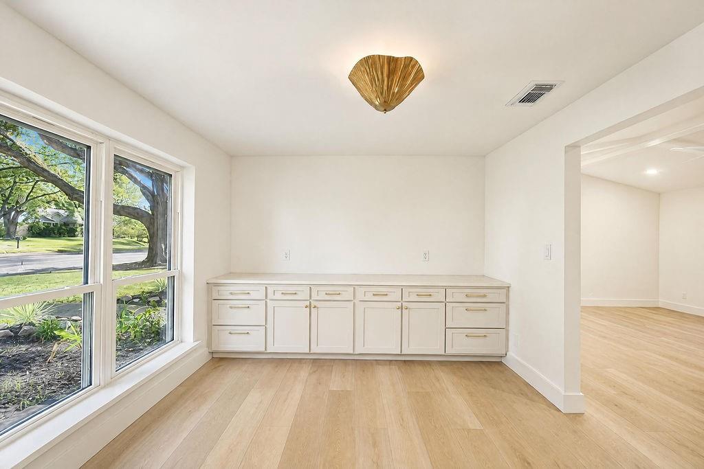 1904 Apollo Road Richardson, TX 75081 - Photo 9 of 40 Light wood-finish flooring, built-in cabinetry with gold-toned hardware, white solid-surface countertop, large windows, and a decorative ceiling light fixture