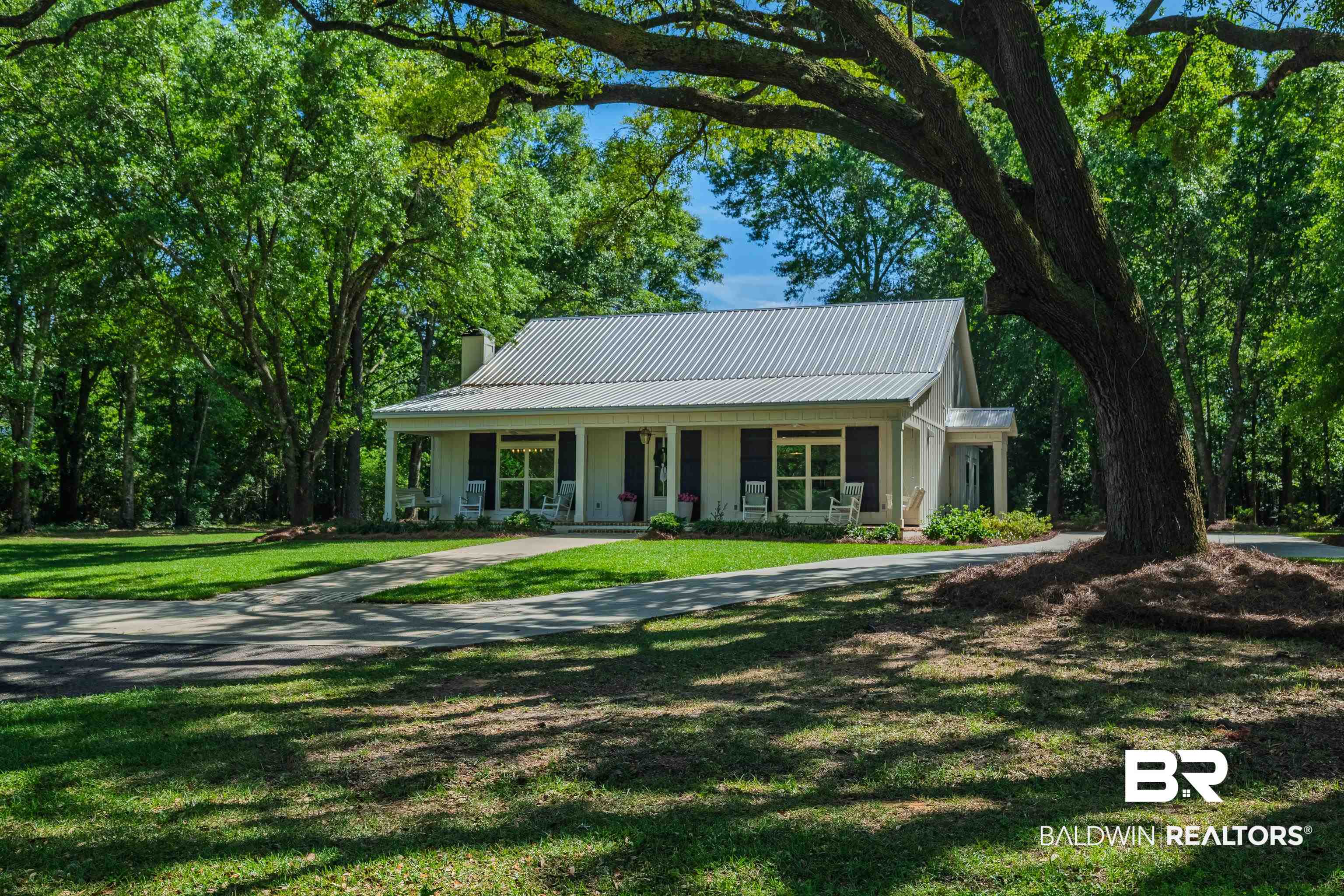 19121 Boothe Road Fairhope, AL 36532 - Photo 1 of 41 View of front of home with covered porch, a chimney, a metal roof, curved driveway, and a front lawn